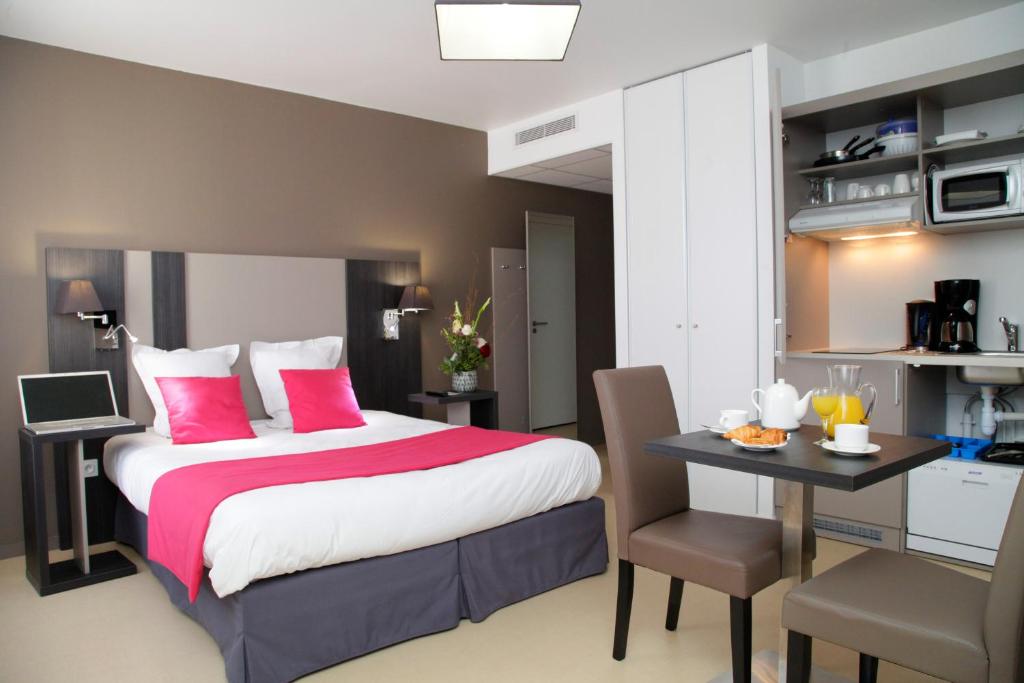 a bedroom with a bed and a desk with a laptop at Odalys City Rennes Lorgeril in Rennes