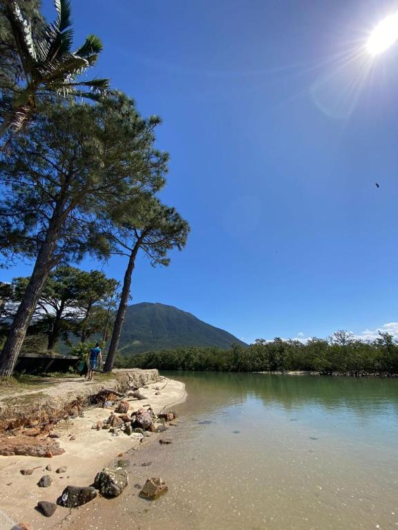 a person standing on the shore of a body of water at Descanse na Praia de Fora in Palhoça
