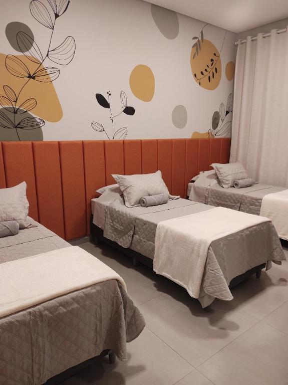 a room with two beds and a wall with flowers at Apartamento novo em São Lourenço in São Lourenço