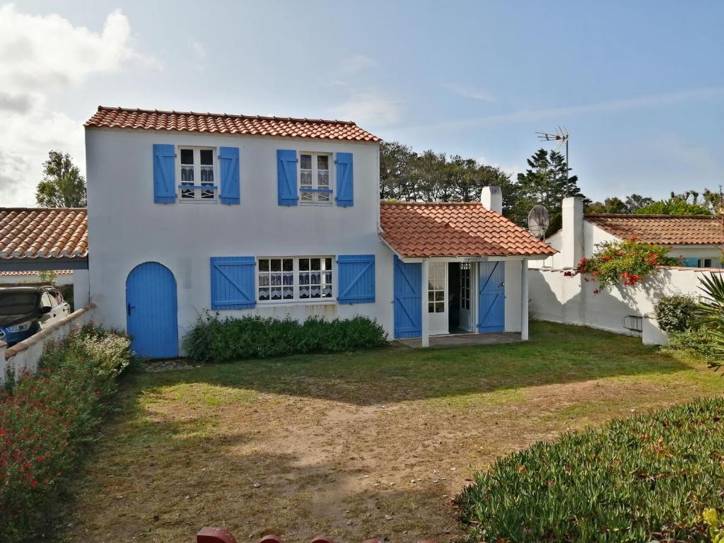 une maison avec des portes bleues et une cour dans l'établissement Maison proche plage, 3 pers, animaux admis - FR-1-823-128, à Noirmoutier-en-l'lle