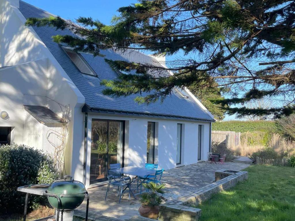 Cette petite maison blanche dispose d'une terrasse et d'une table. dans l'établissement Villa contemporaine spacieuse proche de Sauzon avec jardin - FR-1-418-265, à Sauzon