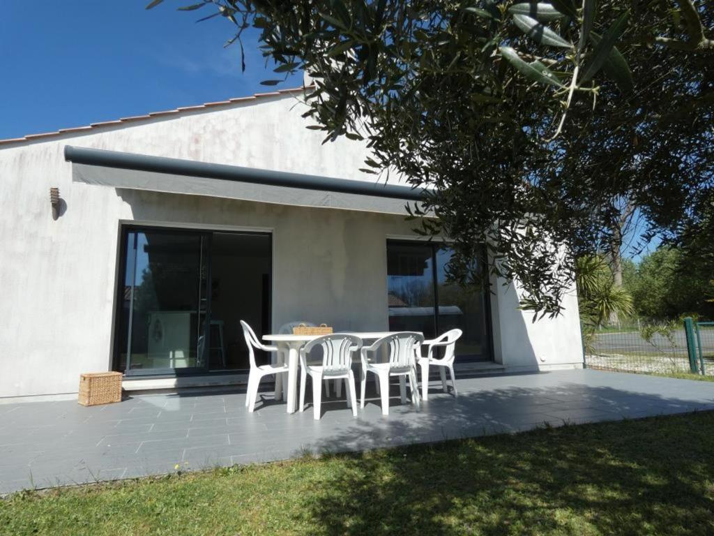 un patio avec des chaises et une table devant un bâtiment dans l'établissement Maison moderne et calme à Notre-Dame-de-Monts, 8 personnes - FR-1-540-321, à Notre-Dame-de-Monts