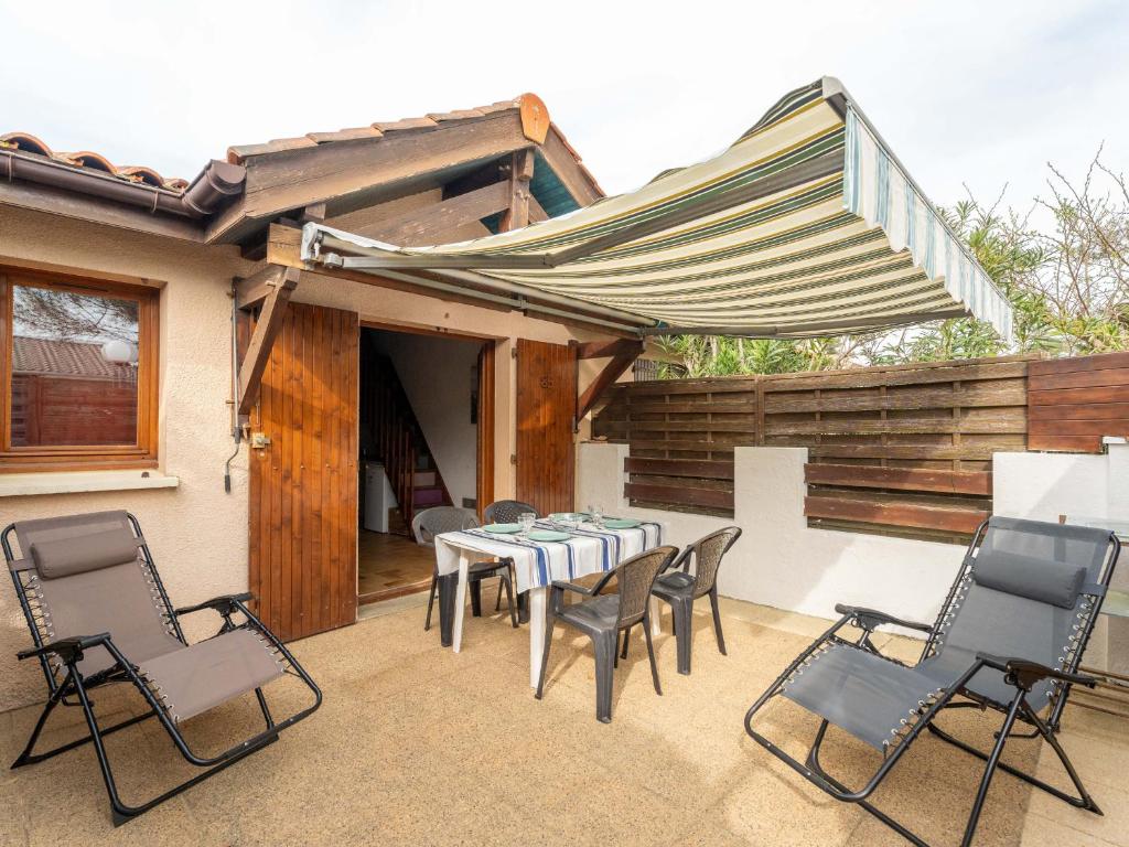 un patio avec une table, des chaises et un parasol dans l'établissement Appartement duplex à deux pas de l'océan pour 4 personnes, cour privée, ménage inclus - FR-1-319-600, à Biscarrosse