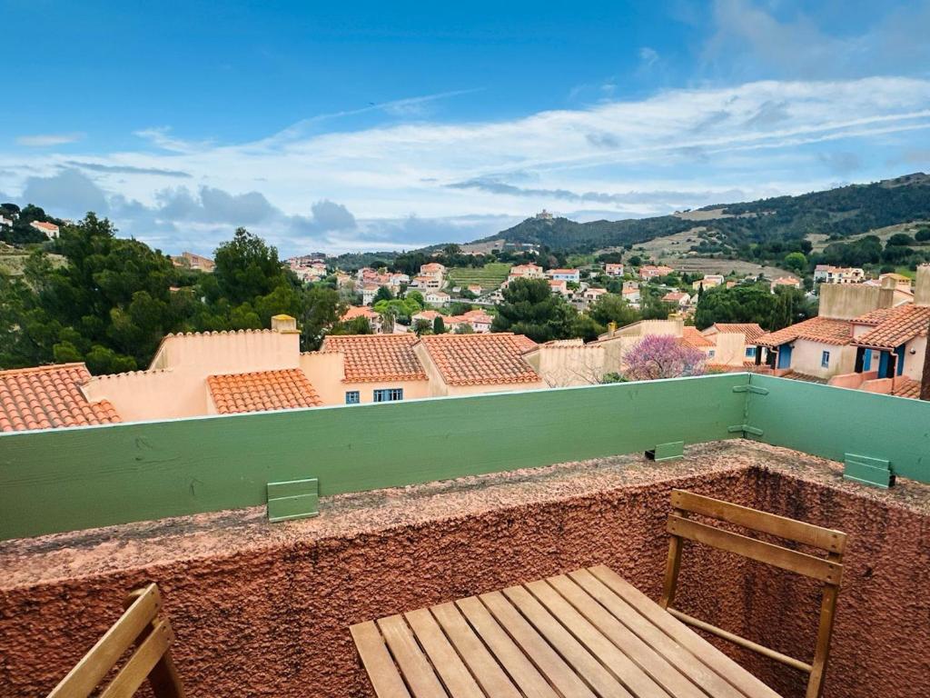 d'un balcon avec une chaise en bois et une vue sur la ville. dans l'établissement Studio charmant à Collioure - Résidence sécurisée - FR-1-309-505, à Collioure