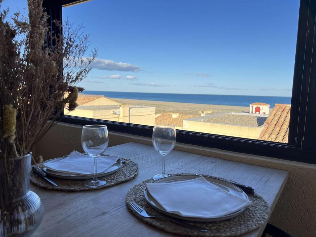 - une table avec deux verres et une vue sur l'océan dans l'établissement Villa T3 rénovée, 4 pers, face mer, clim, WiFi, Port Leucate - FR-1-81-633, à Port-Leucate