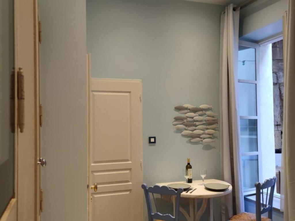 a dining room with a table and a white door at Studio de charme climatisé centre de Pézenas, animaux admis - FR-1-607-212 in Pézenas