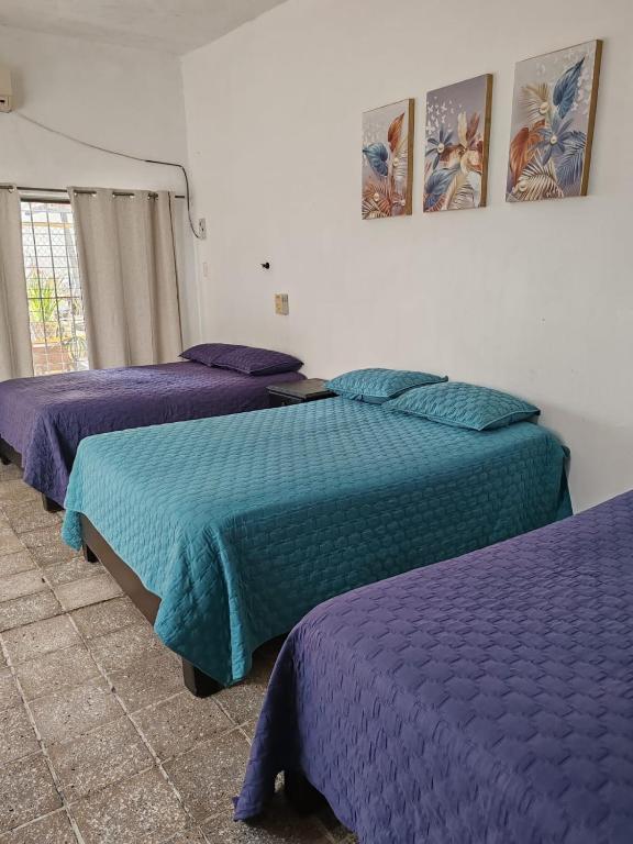 3 camas en una habitación con sábanas moradas en Casa Kika, en Mazatlán
