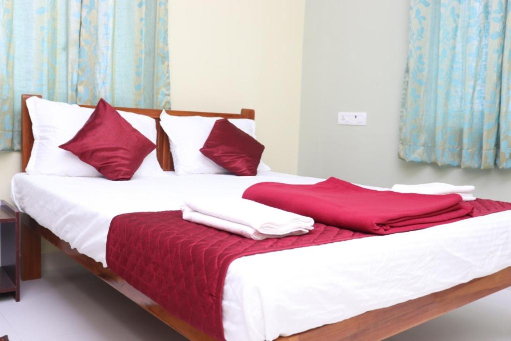 a bed with red and white sheets and pillows at Hotel Starlight Chennai near DLF,L&T,Miot,Tradecenter,Ramachandra medical coll in Chennai