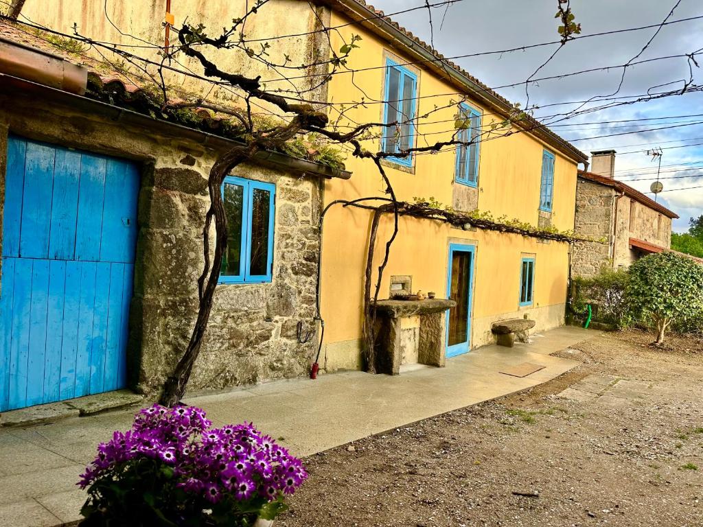 una casa con una puerta azul y flores púrpuras en Casa do Bidueiro, en Luou