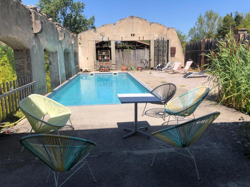 - une piscine avec 2 chaises, une table et une table dans l'établissement La Distillerie, à Couffoulens