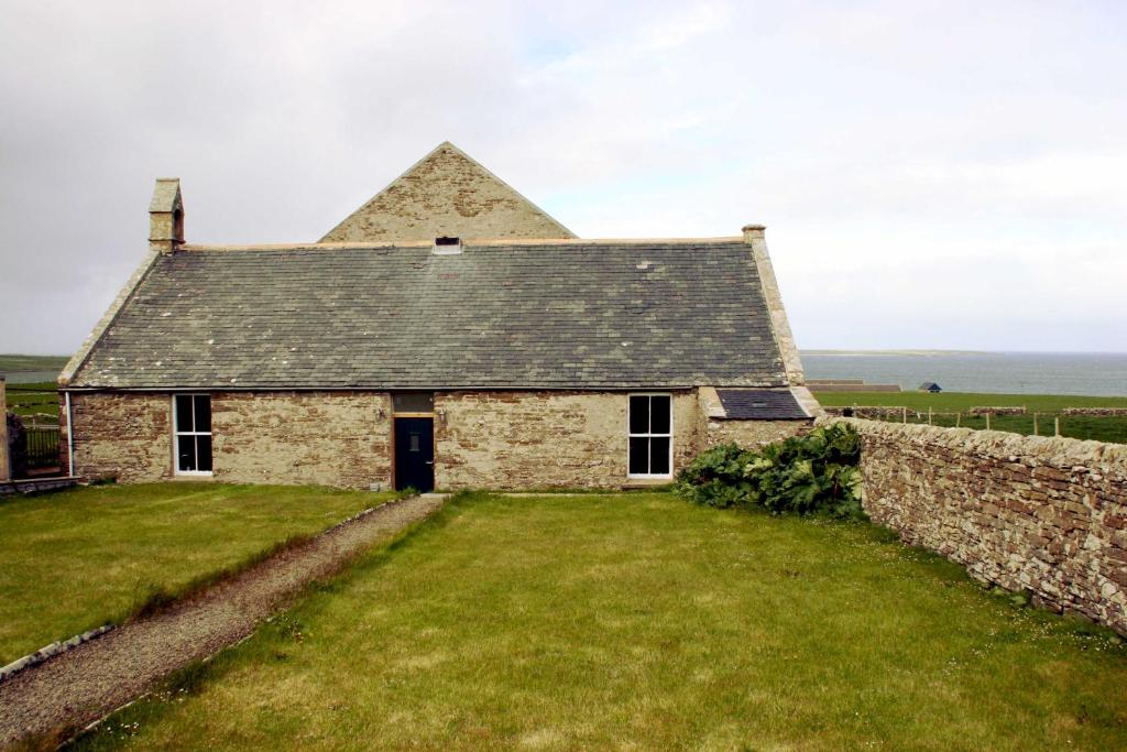 an old stone house with a stone wall at The Reid Hall in Pierowall