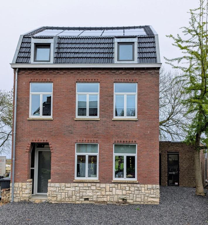een rood bakstenen huis met een zwart dak bij Mijn appartement met sauna en lift in Voerendaal