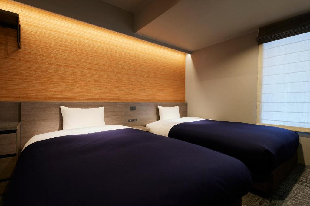 two beds in a room with a window at Minn Gion Sanjo in Kyoto