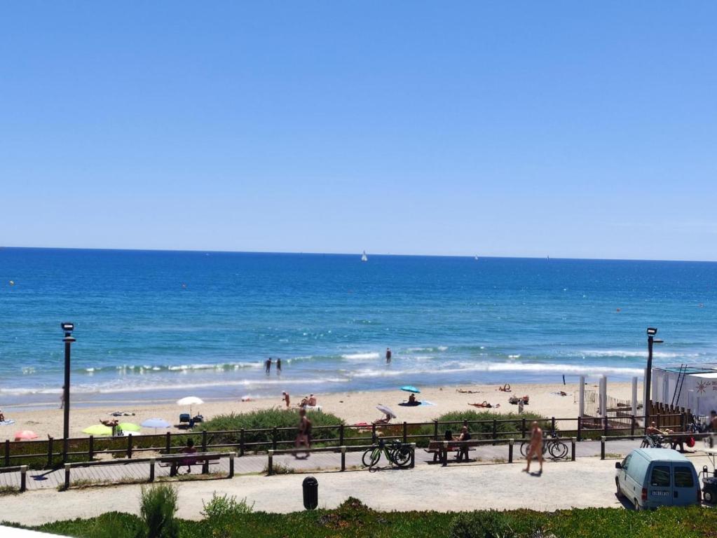 - une plage avec des gens sur le sable et l'océan dans l'établissement Studio 26C, Bat C Héliopolis Village Naturiste, au Cap d'Agde