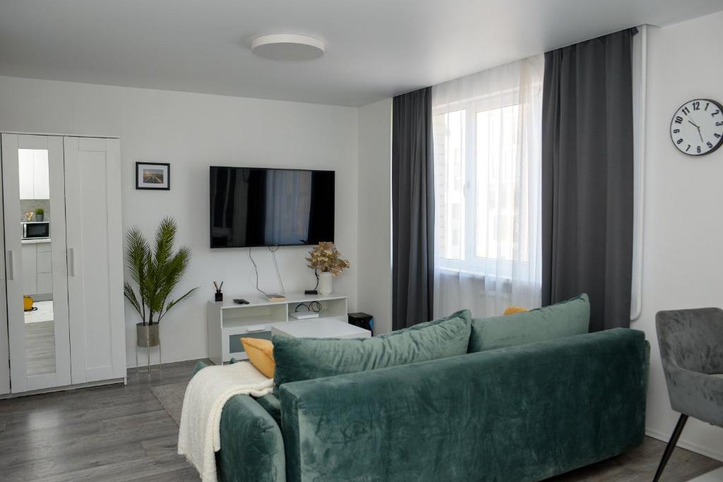 a living room with a green couch and a tv at El Roi Home's in Vilnius