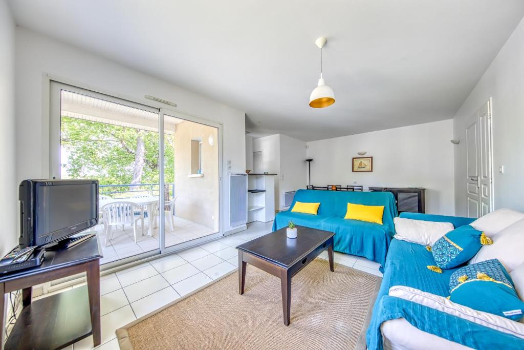 Una sala de estar con un sofá azul y un televisor. en 3 pièces - Piscine - Proche plage, en Soulac-sur-Mer