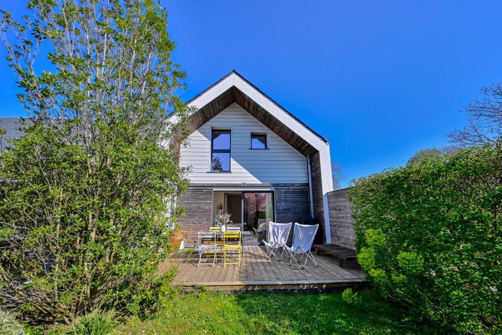 une maison avec une terrasse dotée de tables et de chaises dans l'établissement L'Annëxe de Kerogile - Avec jardin et terrasse, à Carnac