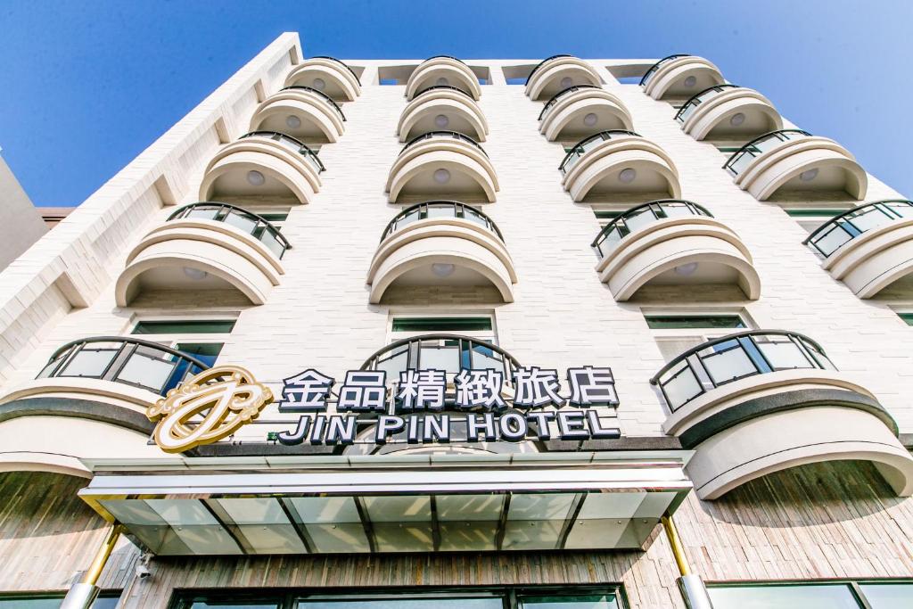 Um edifício alto e branco com uma placa do Hotel Jim Pan. em Jin Pin Hotel em Magong