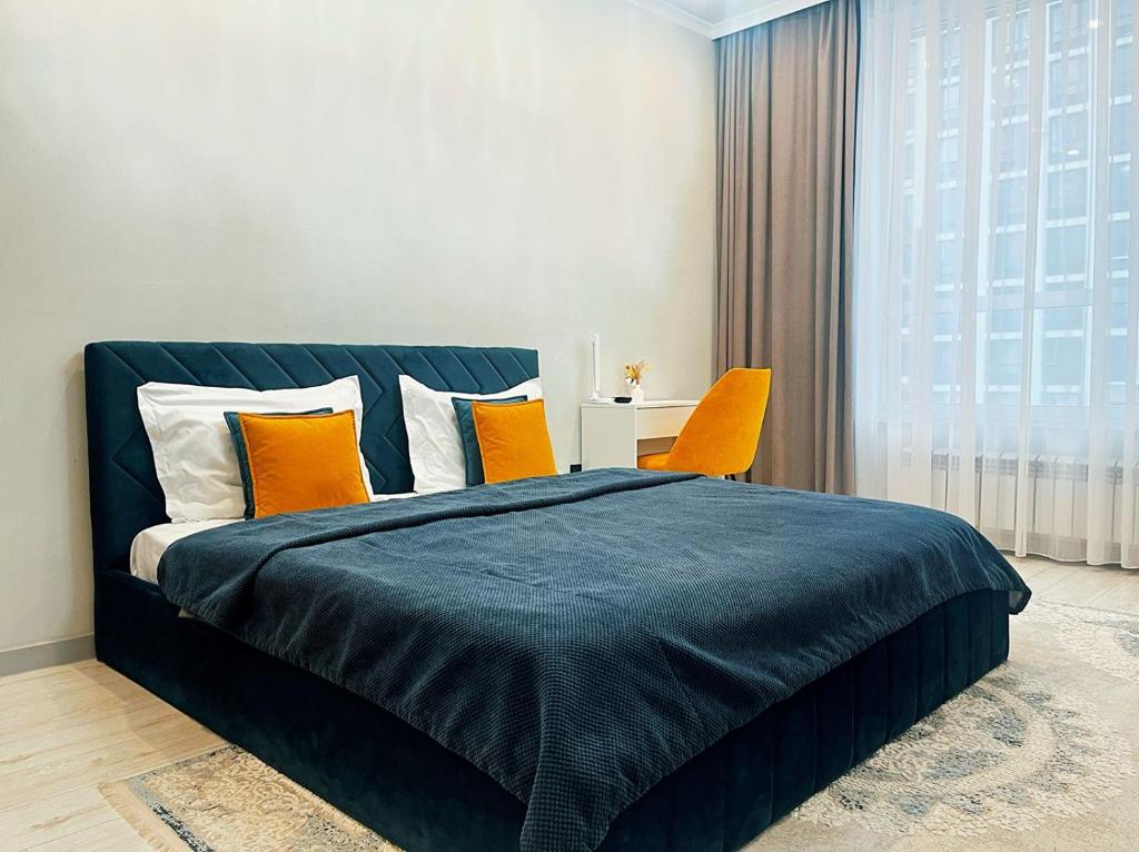 a bedroom with a bed and two orange chairs at Уютная квартира на Левом берегу, ТРЦ Хан Шатыр in Astana