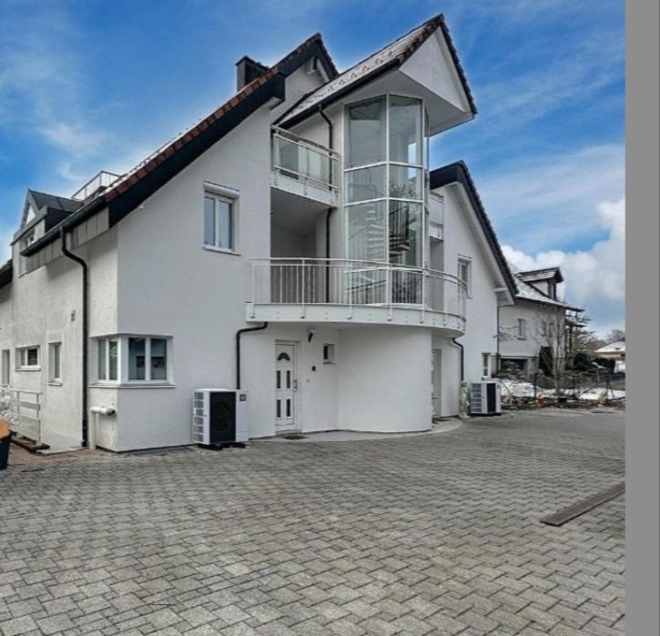 a large white house with a balcony on a driveway at Grand appartement frontière suisse in Leymen