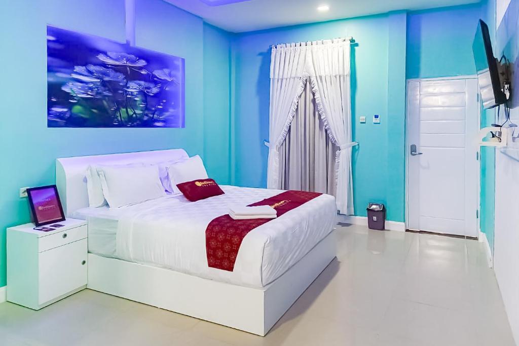 a bedroom with a white bed and blue walls at RedDoorz Premium Hotel Sopo Holong Sibolga in Sibolga