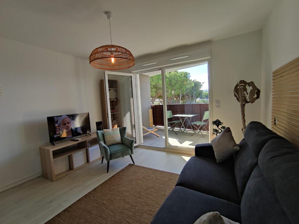 un salon avec un canapé noir et une télévision dans l'établissement Studio 218, WELLNESS Cap d'Agde, Centre de Tennis, au Cap d'Agde