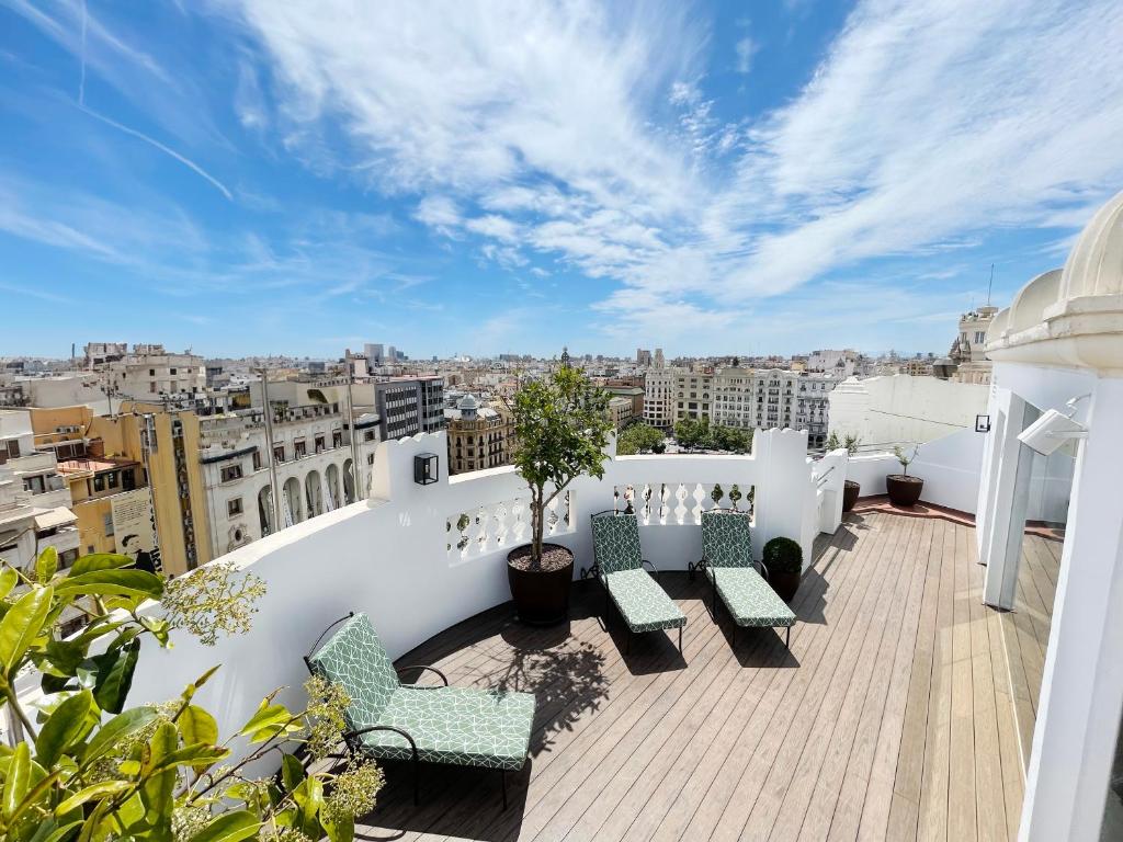a balcony with chairs and a view of a city at Melia Plaza Valencia in Valencia