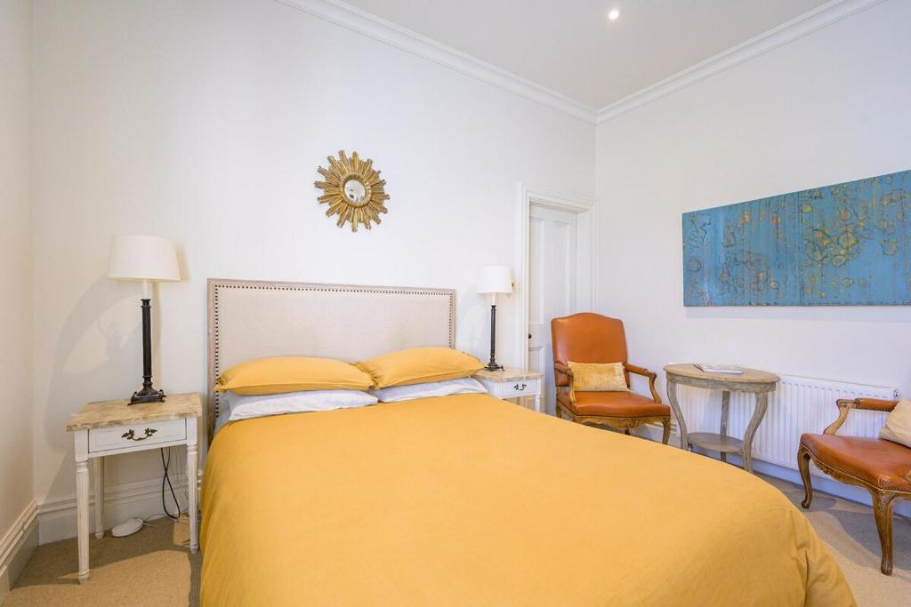 a bedroom with a yellow bed and two chairs at Nile Street Studio in Nelson