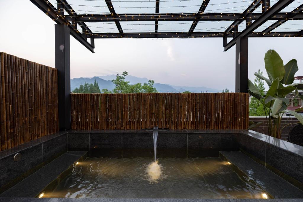 a patio with a water fountain and a wooden fence at 青城山泉青小院温泉中式民宿 in Taiping