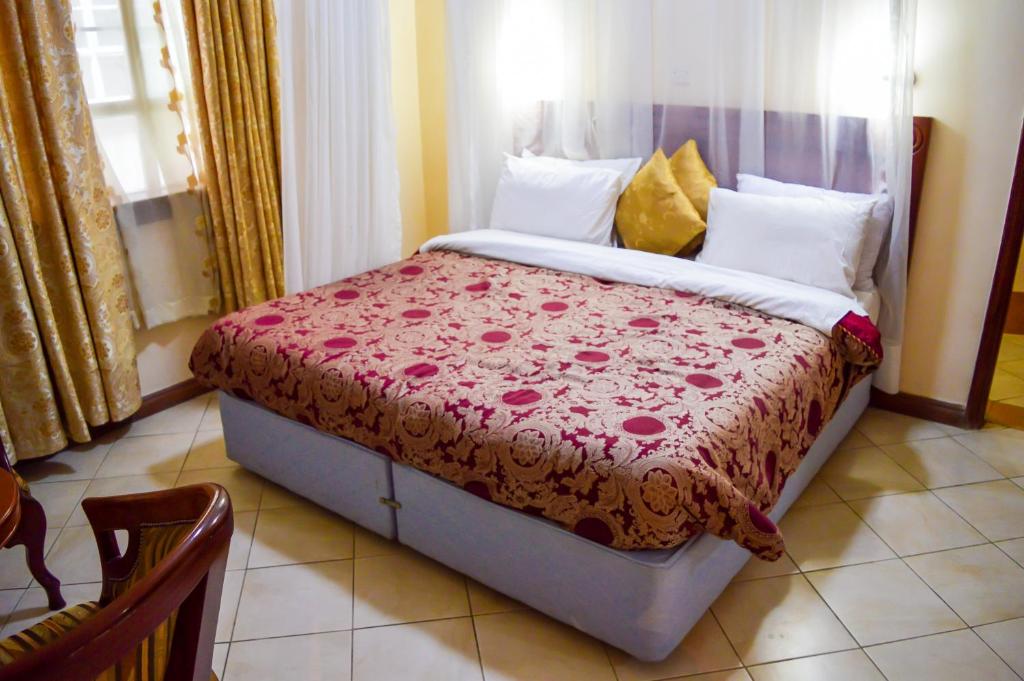a bedroom with a bed with a red comforter at Anthena Hotel in Athi River