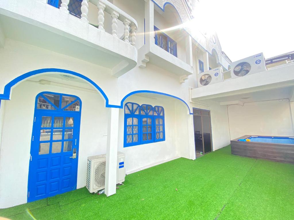 a house with a blue door and green grass at 曼谷市中心大空间6卧室花园泳池别墅 in Bangkok