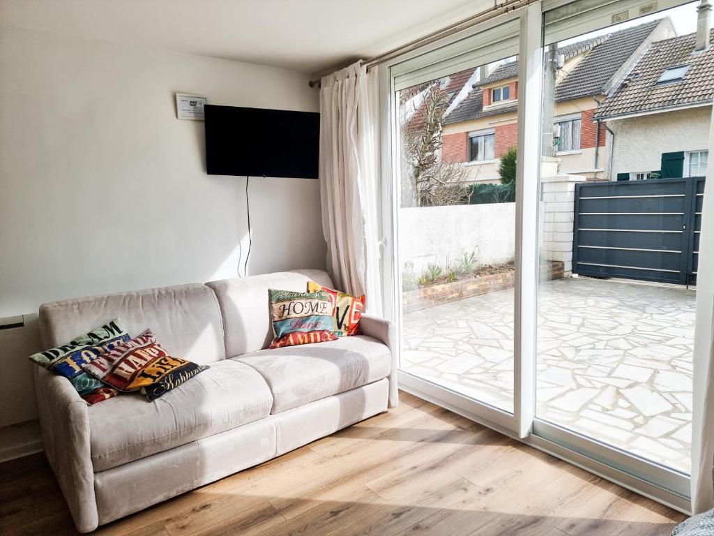 ein Wohnzimmer mit einer Couch und einer Glasschiebetür in der Unterkunft Grand Studio Lumineux pour 4 personnes in Bois-dʼArcy