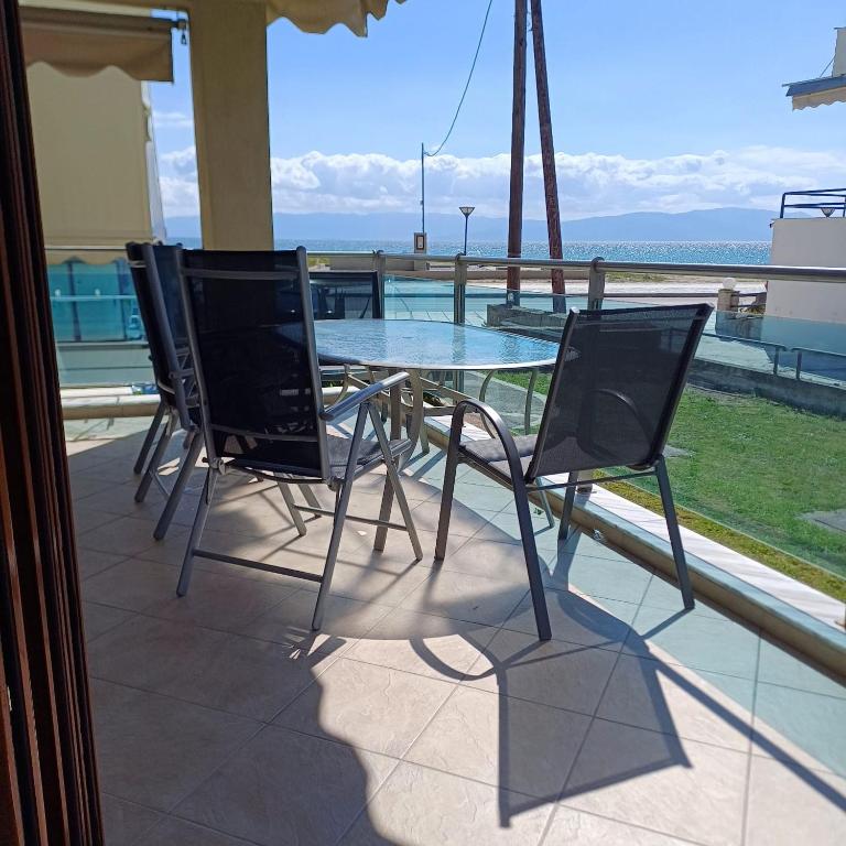 a glass table and chairs sitting on a patio at Paralia Ofriniou Sea view apartment in Orfánion