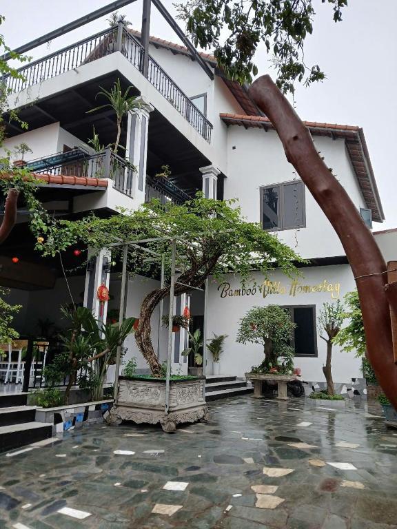a white building with a tree in front of it at BamBoo Villa Homestay in Ninh Binh