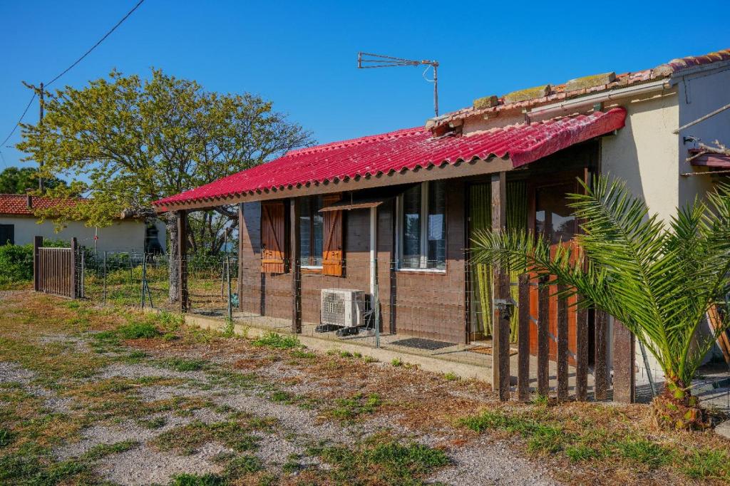 une maison en briques avec un toit rouge et une clôture dans l'établissement Cabane de pêcheurs, à Pérols