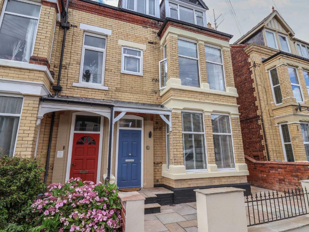 ein Backsteinhaus mit einer roten Tür und einer blauen Vordertür in der Unterkunft Coral Villa in Bridlington
