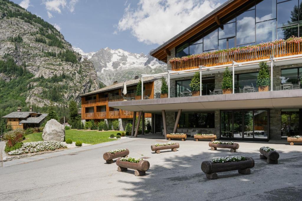 budynek z ławkami przed nim z górami w obiekcie Grand Hotel Courmayeur Mont Blanc, by R Collection Hotels w mieście Courmayeur