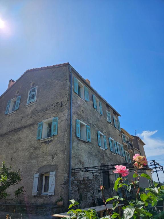 - un vieux bâtiment en pierre avec des fenêtres bleues et des fleurs dans l'établissement Chambre parentale, à Rapale