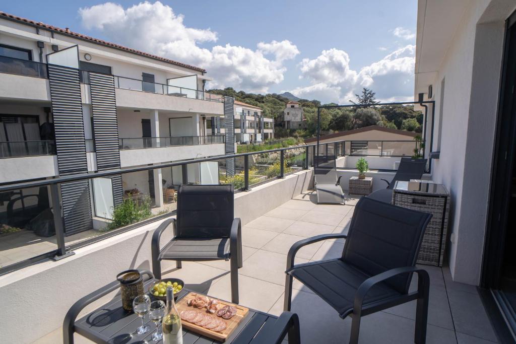 un balcon avec deux chaises et une table sur un immeuble dans l'établissement Studio moderne et lumineux, proche centre ville, à Propriano