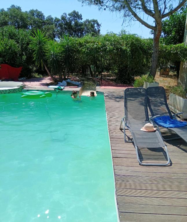 - une piscine avec une terrasse et 2 chaises dans l'eau dans l'établissement Maisonnette Soleil, à Nîmes