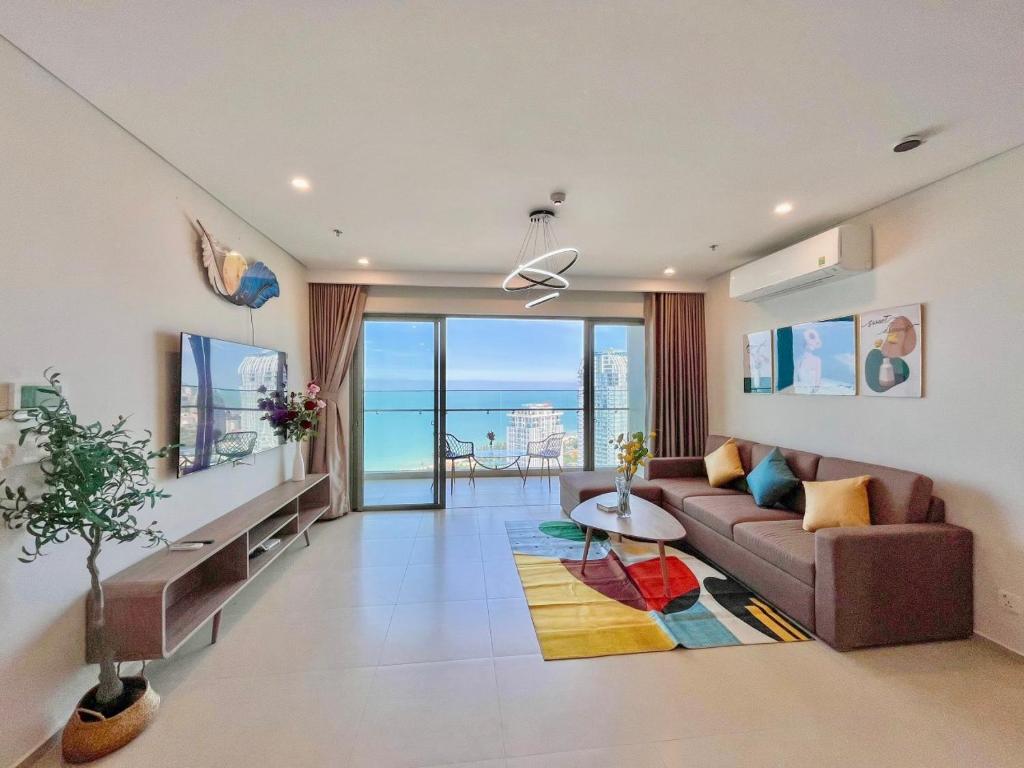 een woonkamer met een bank en uitzicht op de oceaan bij THE SÓNG Apartment Vũng Tàu - Trinh's House in Vung Tau