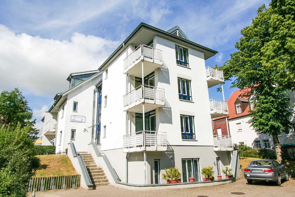 ein weißes Gebäude mit Balkon und Auto in der Unterkunft Residenz Düne III - Ferien-Apartments in Boltenhagen in Boltenhagen