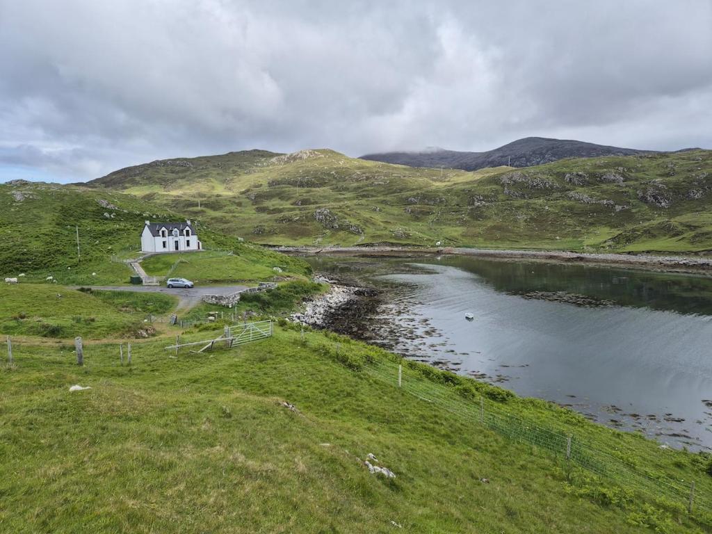 a house on a hill next to a body of water at Tigh an Data, Borrisdale, South Harris in Rodel