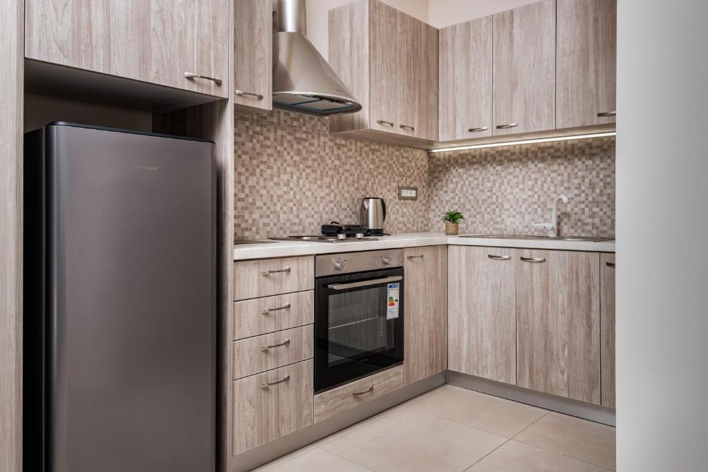 eine Küche mit Holzschränken und einem Kühlschrank aus Edelstahl in der Unterkunft Katsaros Luxury Apts 5 min walk to beach in Planos