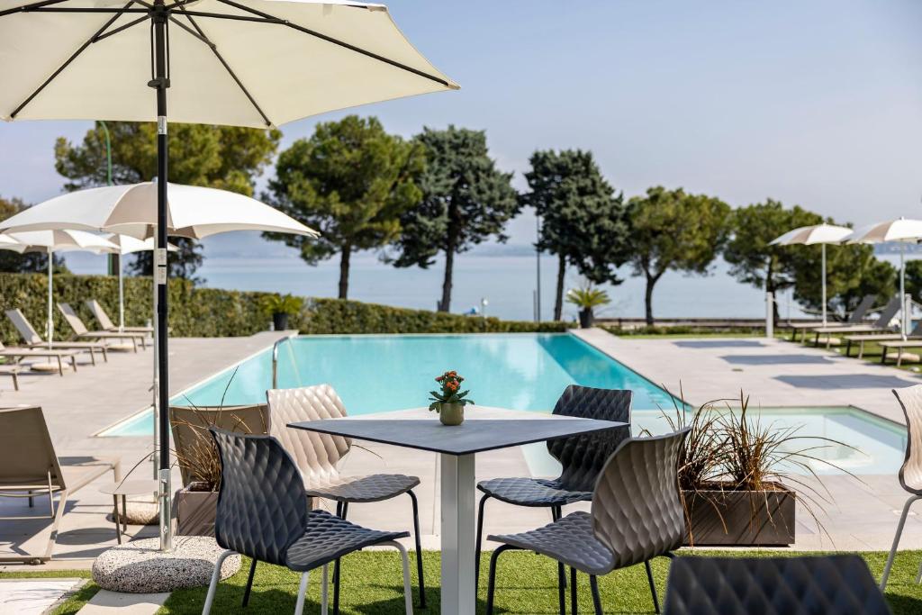 a table and chairs with umbrellas next to a pool at Vision Hotel in Peschiera del Garda