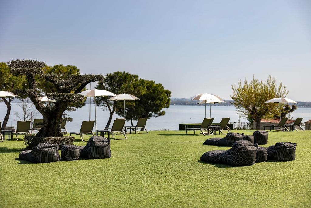 a group of chairs and umbrellas on the grass at Vision Hotel in Peschiera del Garda
