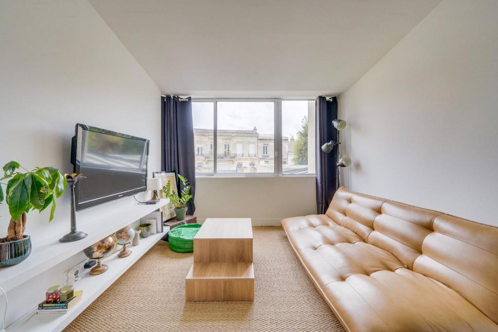 un salon avec un canapé et une télévision dans l'établissement Charming, modern flat with private parking, à Bordeaux