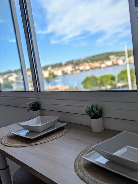 - une table avec deux plats blancs au-dessus d'une fenêtre dans l'établissement Appartement vue mer toute commodité, à La Seyne-sur-Mer