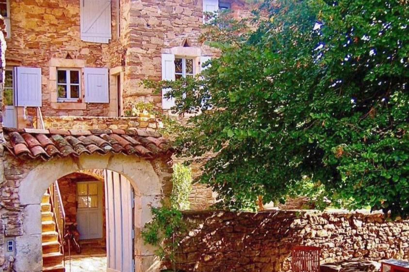 une ancienne maison en pierre avec une arche en face de celle-ci dans l'établissement La Boussonie, Mas de caractère au pays des Vans, aux Vans