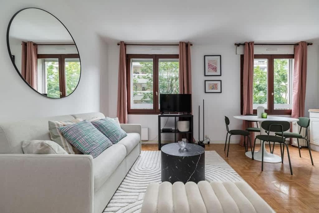 - un salon avec un canapé blanc et un miroir dans l'établissement Spacious Apt 4PAX - Paris Courbevoie, à Courbevoie